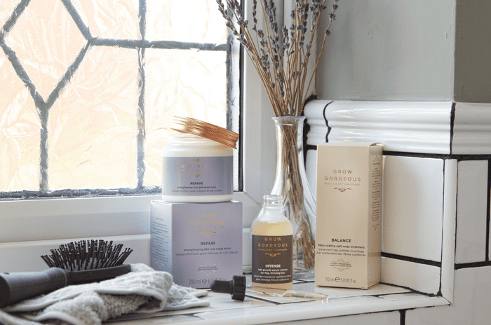 Four grow gorgeous products next to hair brush and flowers