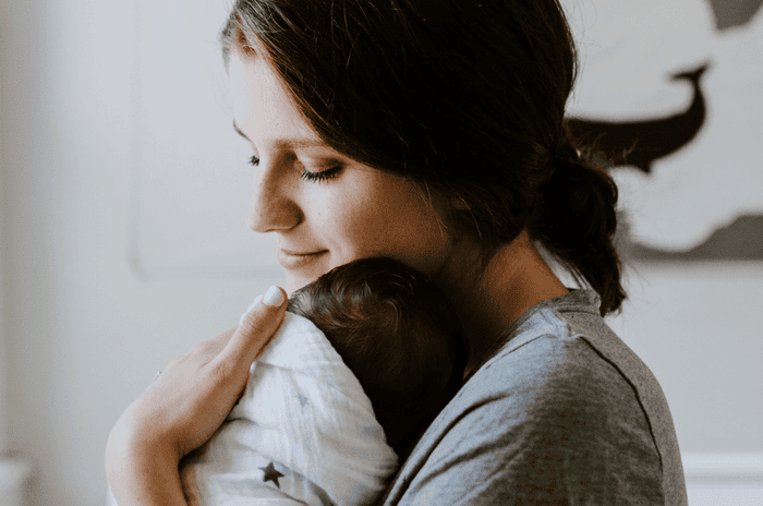 Postpartum mother holding child in her arms