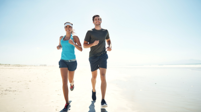 man and woman running on the beach