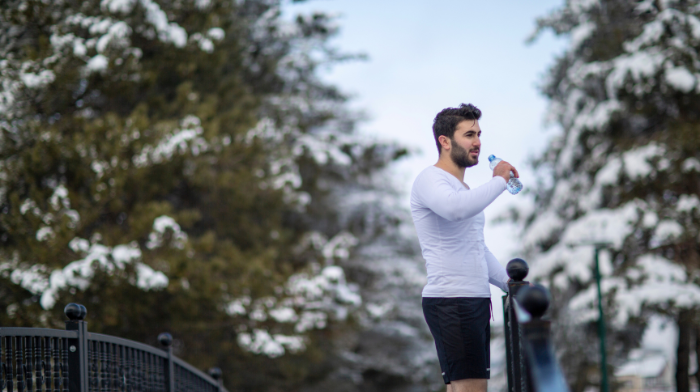 man drinking water outside in the winter