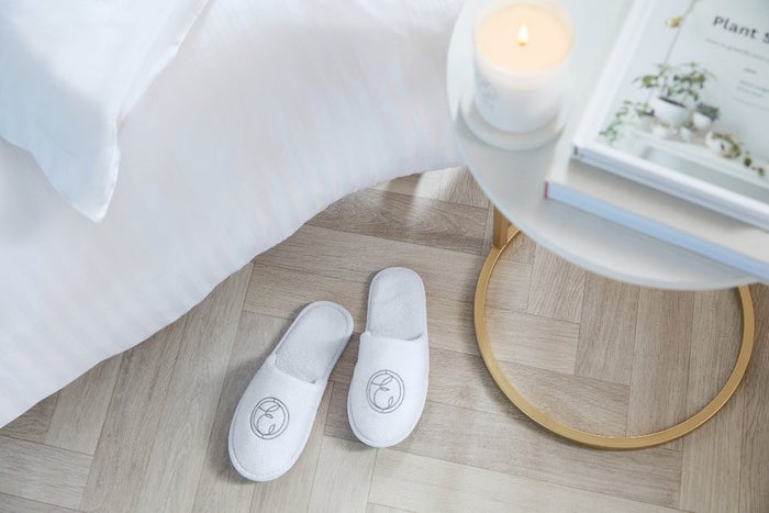 slippers and candle beside white bed