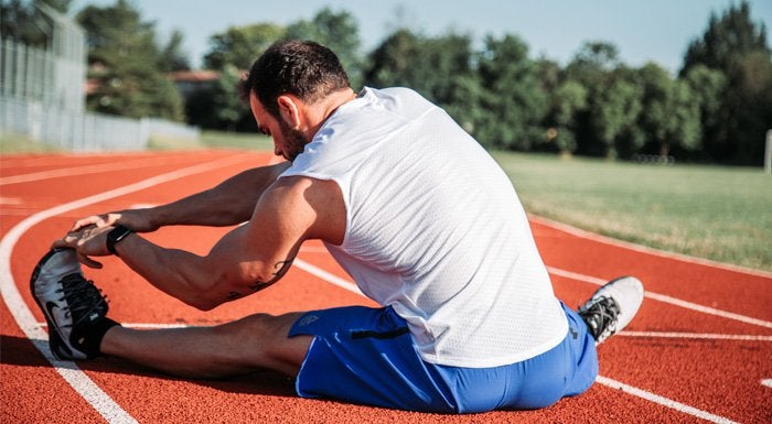 man stretching on a running track