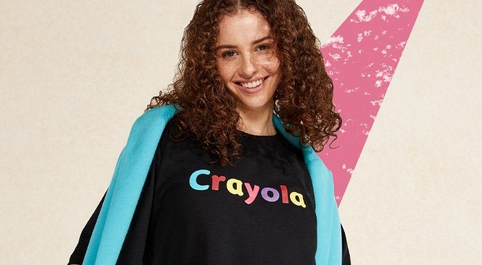A woman wearing the MP x Crayola t-shirt with the 'Crayola' logo in a colourful design.