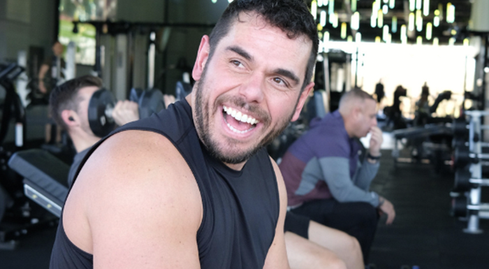 Ross Edgley sits upright and smiling on a bench at Myprotein's gym