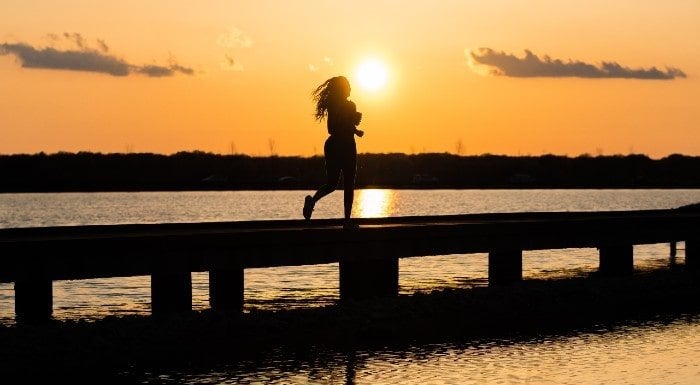 Biegnąca kobieta o zachodzie słońca by utrzymać zdrowie psychiczne