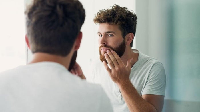 man trying to stop a shaving cut from bleeding