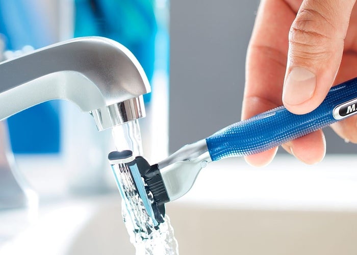 Gillette razor being rinsed under a tap.