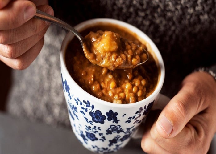 man eating homemade soup out of a mug