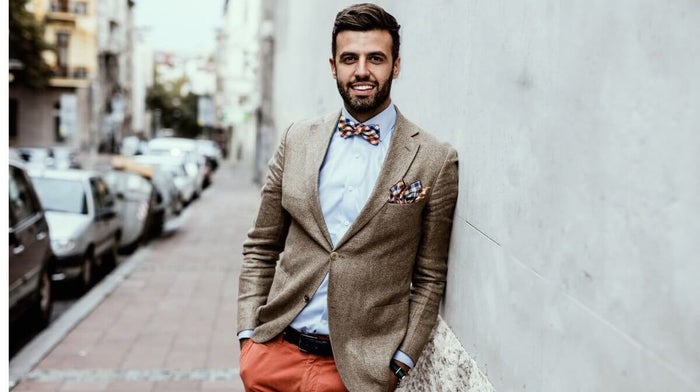 man looking stylish in orange trousers, a smart blazer and quirky bow tie