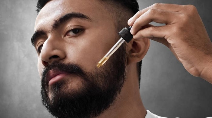 man applying fragrance to his beard