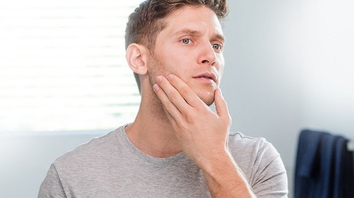man inspecting his clean face in the mirror