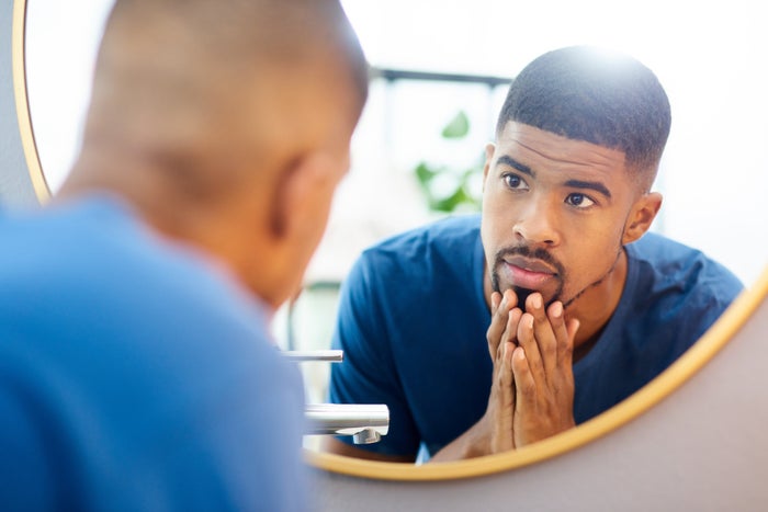 man with shaped goatee combing beard with fingers