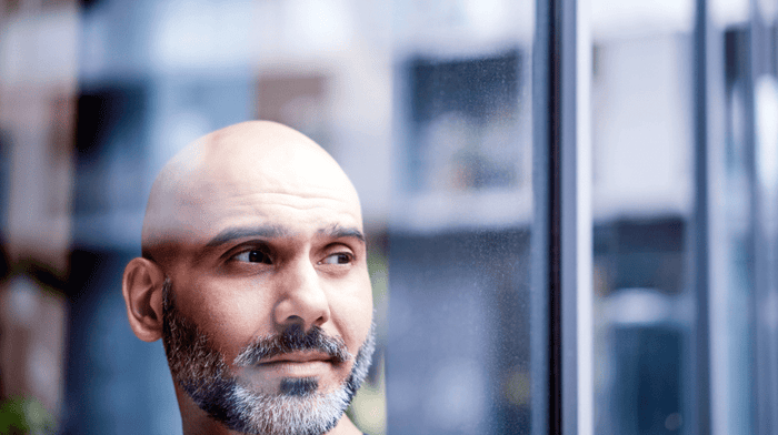 Man with bald head and beard looking through window 