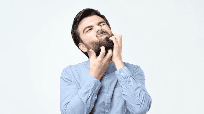 Man scratching itchy beard