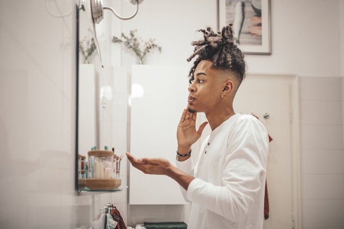 Young man applying beard oil