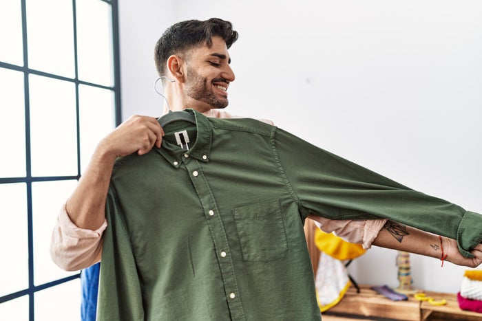 Young Hispanic man with short beard trying on shirt