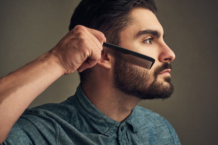 Young man combing beard 