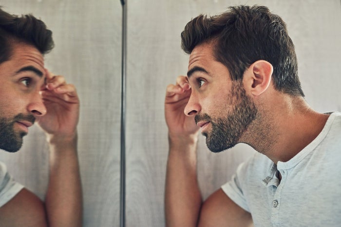 Man with a rugged beard looks in to a mirror and wonders if the Gillette King C. range can help his grooming routine