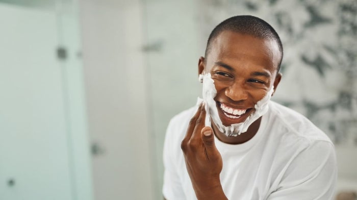 A man with shaving foam smiles in a mirror | Gillette UK