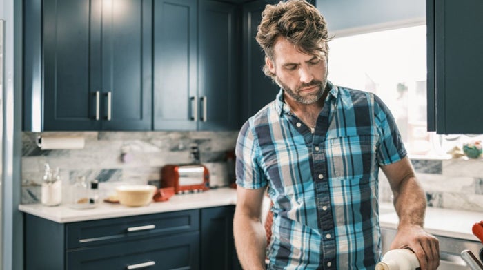 A rugged man with a mullet and beard pours a drink in his kitchen | Gillette UK