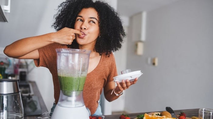 woman making green smoothie in blender