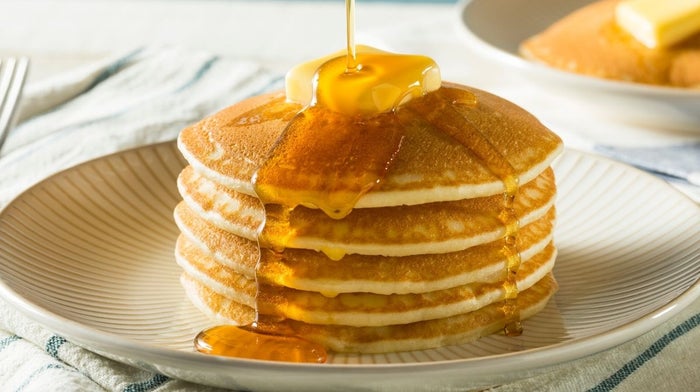 stack of homemade pancakes topped with butter and syrup