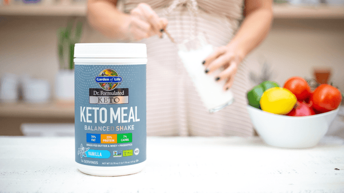 woman scooping keto protein powder into glass