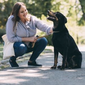 A woman petting her dog outside.