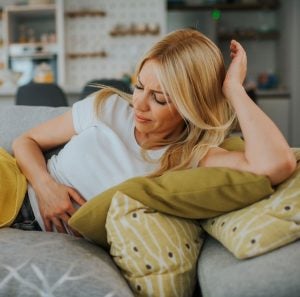 A woman with stomach pain on a sofa.