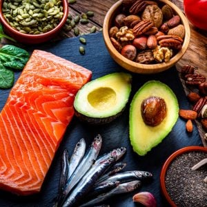 An assortment of food such as salmon, avocado, nuts, spinach and grains. 