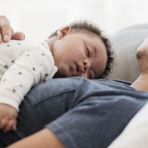 A baby sleeping on his dad's chest. 