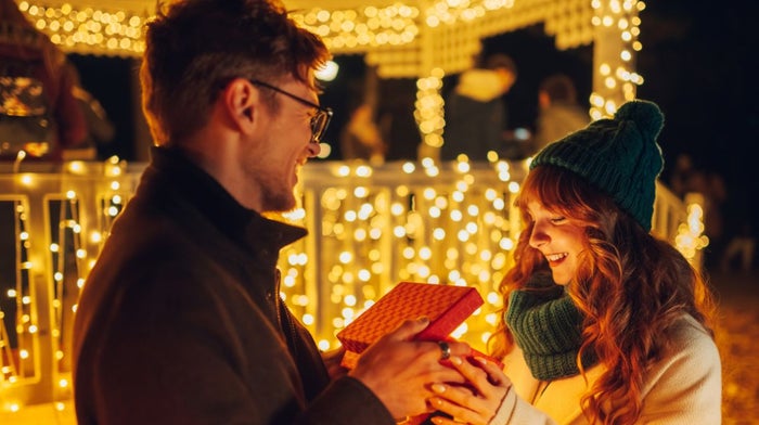 A man gifts his partner with a luxury holiday gift set.