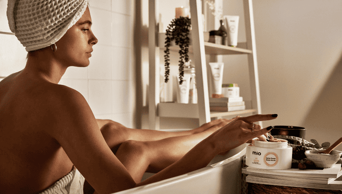 woman in bath with mio solar power body scrub