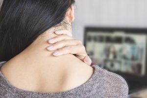 woman having neck pain while working on computer laptop