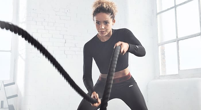 female athlete using battle ropes