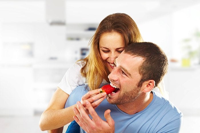 happy young couple eating strawberries together