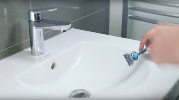 Hand-tapping Gillette razor against a sink.