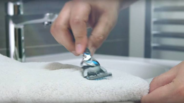 Hand rubbing Gillette razor across a towel.