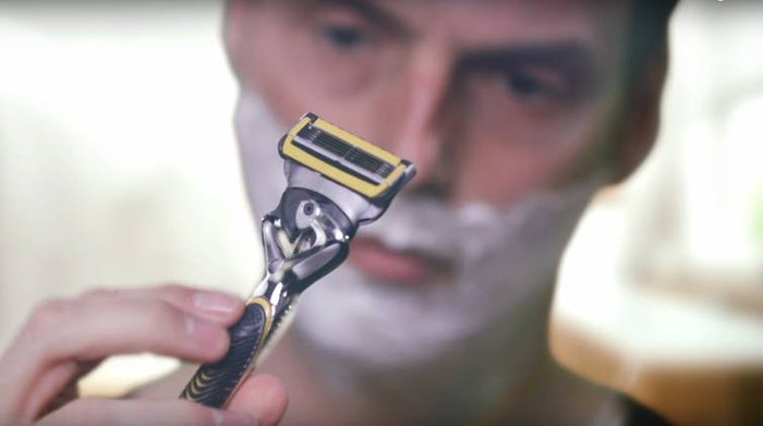 Shaving with five-bladed Gillette razor in yellow and a moisturising layer 