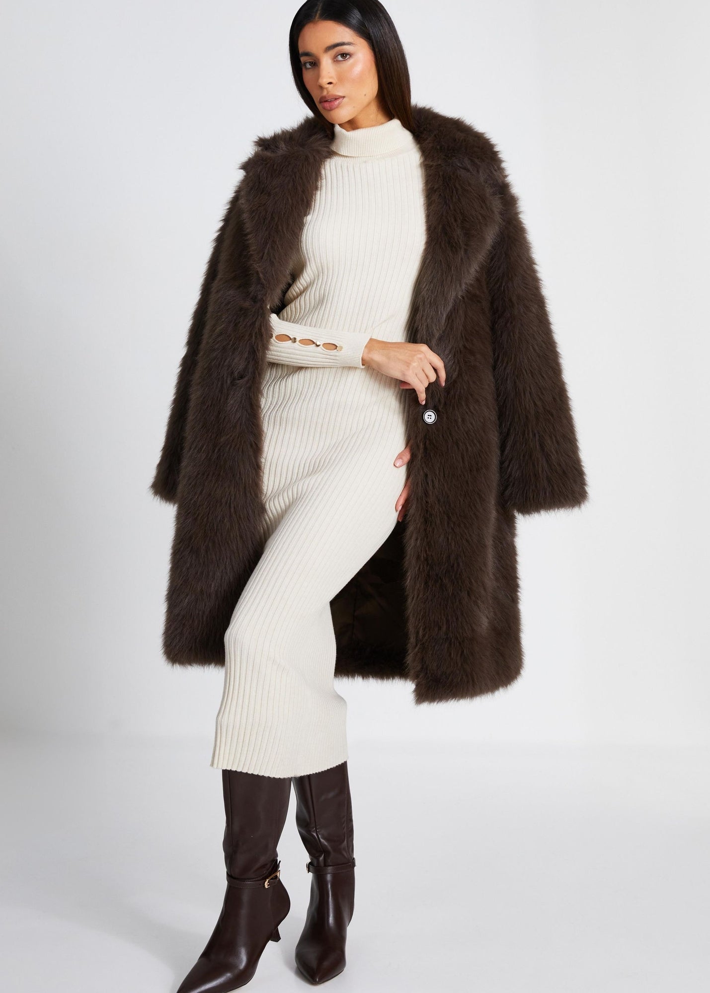 Woman in brown fur coat and cream knit sweater dress