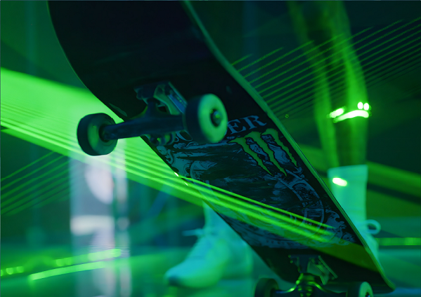 Man carrying a Monster Energy surfboard on a glowing green background