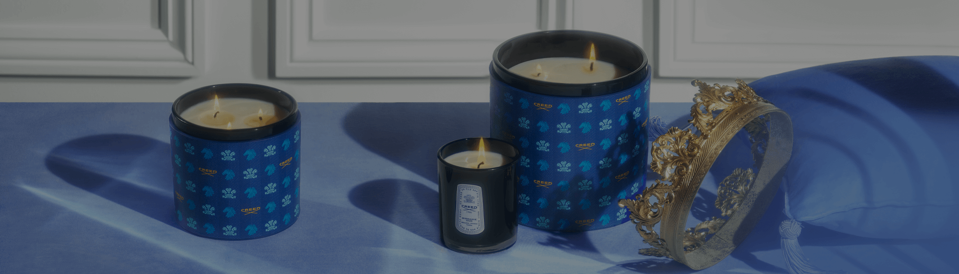 Creed small candle and medium & large leather candles next to crown