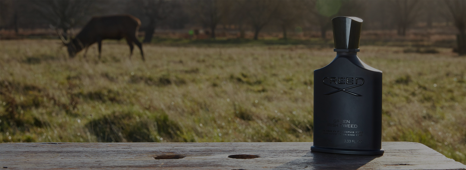 Bottle of Green Irish Tweed on bench in field with deer in background