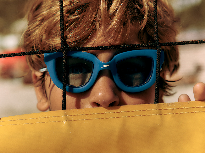 Shop Sunny G goggles – two small boys lying on striped towels wearing Sunny G goggles in blue and white.