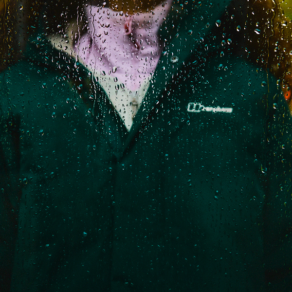 A image taken through a window with rain down it of a close up of someone wearing a Green Berghaus Jacket