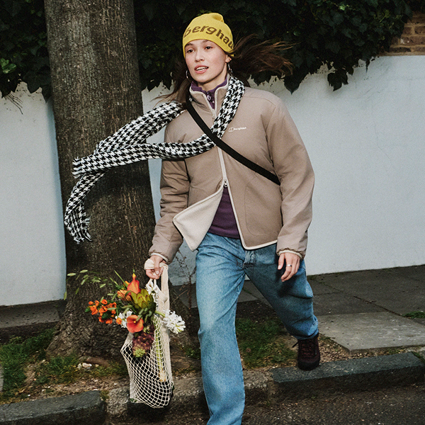 A woman walking in a hat and a fleece in the wind