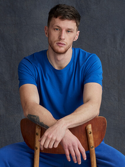 model sat wearing blue t shirt and blue joggers