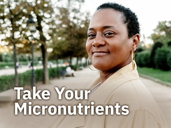 Woman smiling at pointing at apple with text overlay "take your micronutrients"