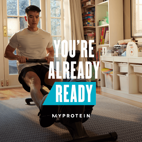 A woman wearing MP gym clothing sat on a window ledge stretching with the text 'You're Already Ready - MYPROTEIN' overlaying the image.